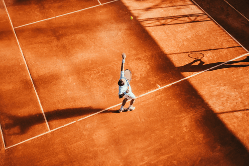 tennis player serving on clay court